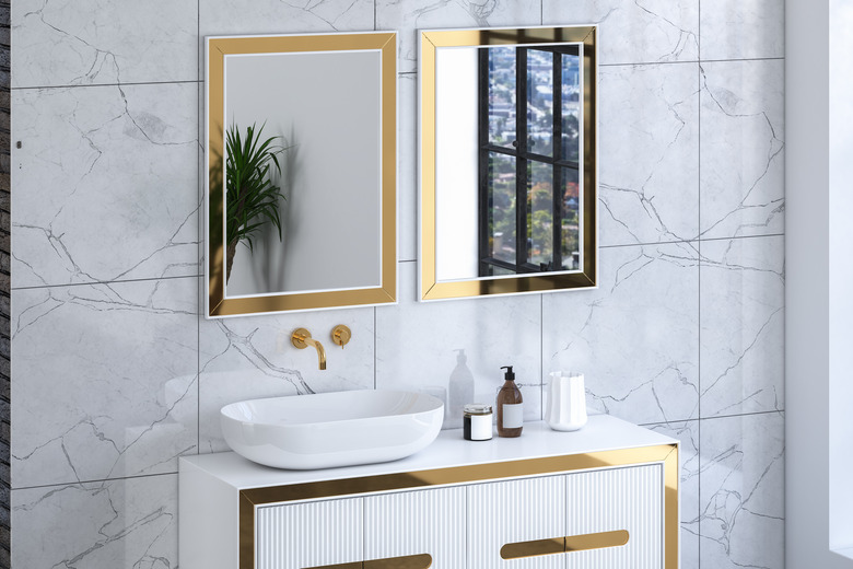 Close up of luxury sink with square mirrors are hanging in on white marble wall,