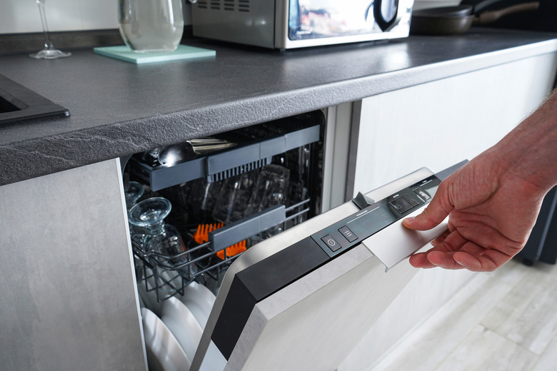 A man opening and closing the dishwasher. Washing dishes in the dishwasher. The man cares about the house, does his homework.