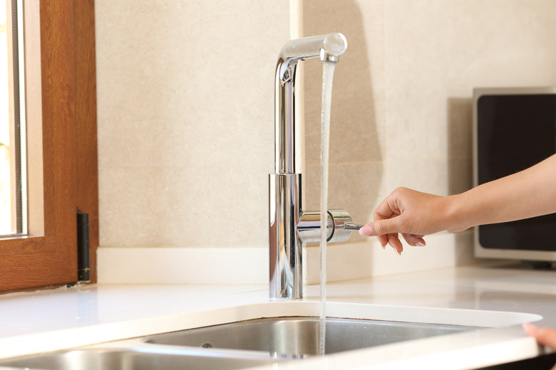 Woman opening kitchen faucet.