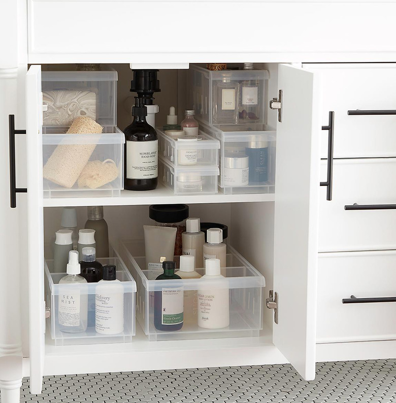 Multi size and shape plastic storage containers inside a cabinet underneath a bathroom sink