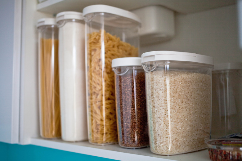 Stocked kitchen pantry with food - pasta, buckwheat, rice and sugar . The organization and storage in kitchen of a case with grain in plastic containers.