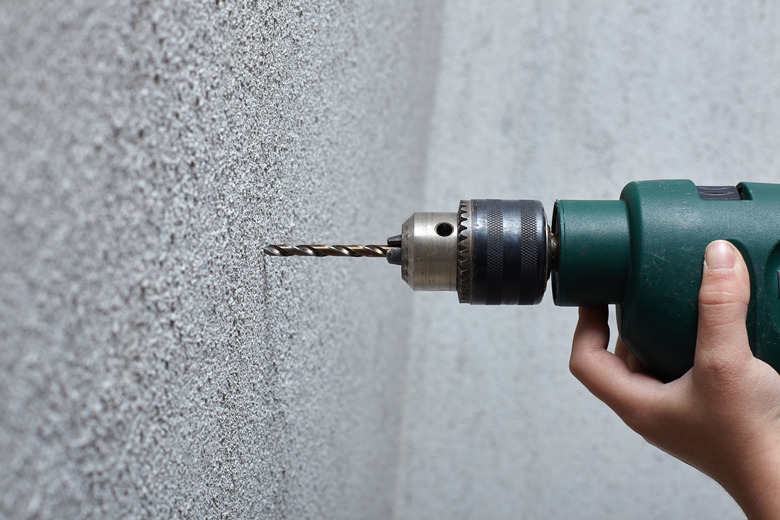 Worker drilling a hole into the wall with an electric drill.