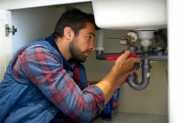 Plumber at work under sink.