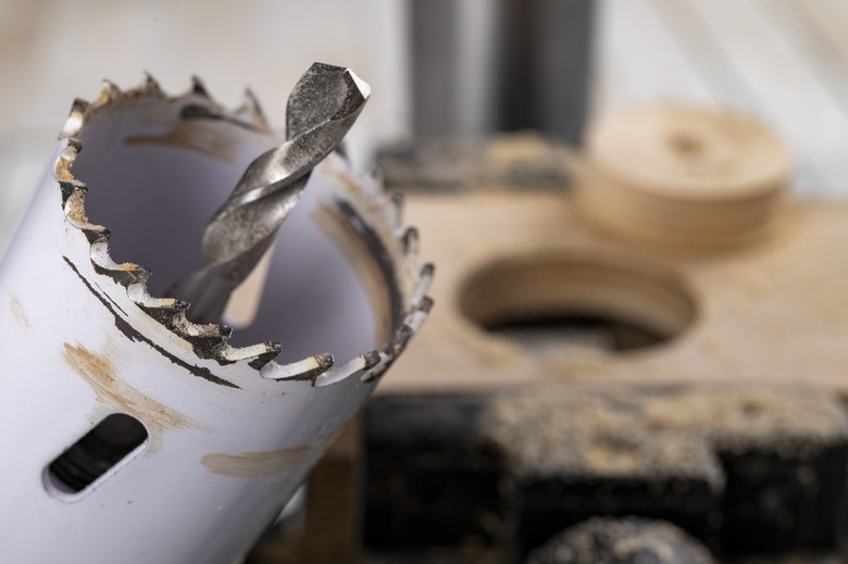 Drilling metal hole saw in a piece of wood. Making holes in a carpentry workshop.