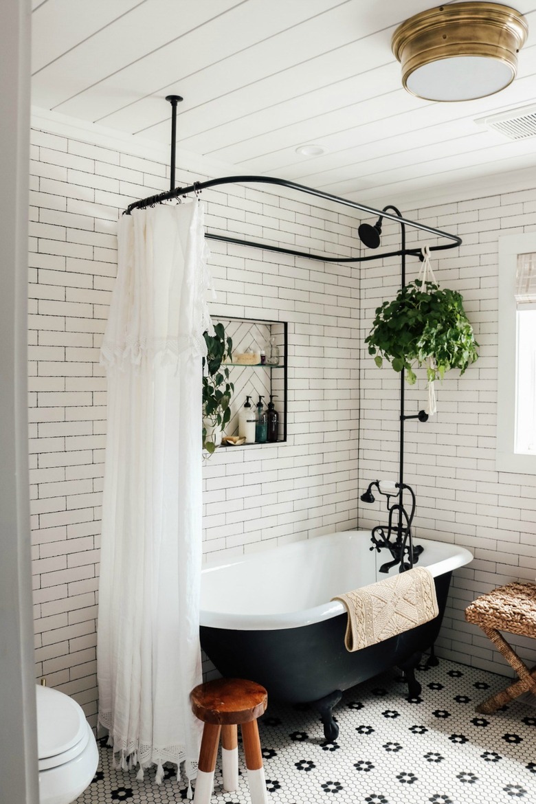 subway tiled bathroom with cast iron claw foot tub and black shower fixtures