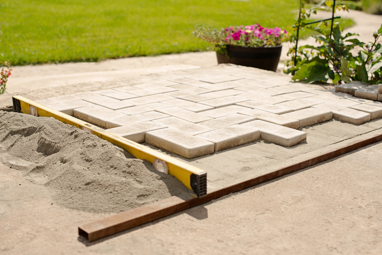 Laying paving stones in layers. Garden brick pathway paving. Laying concrete paving slabs in house courtyard on sand foundation base.