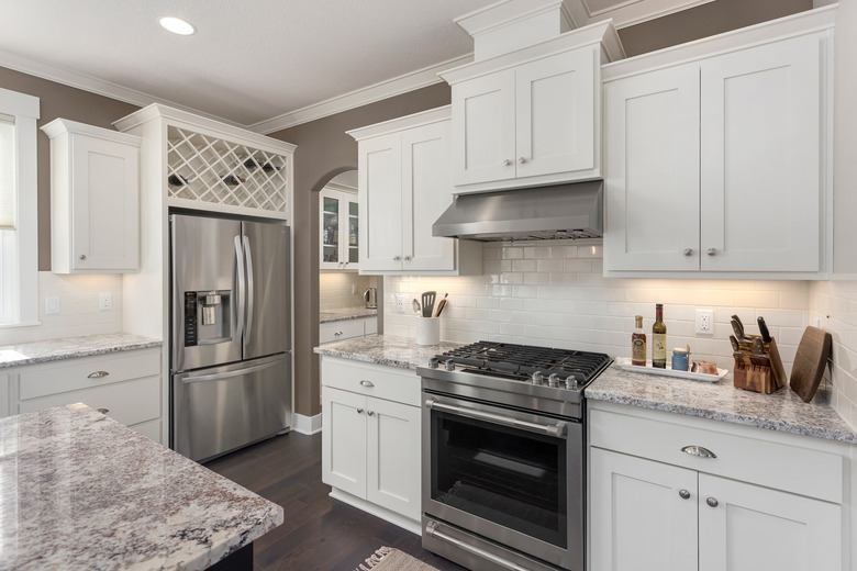 beautiful kitchen in new luxury home with island, stainless steel appliances, and hardwood floors.