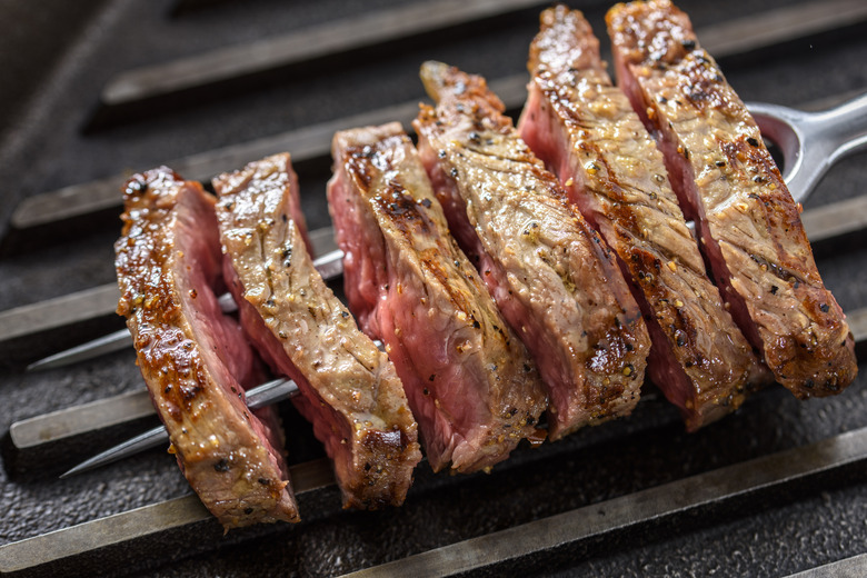 Slice of Grilled Steak with Seasoning on a Fork and Cast Iron Grill