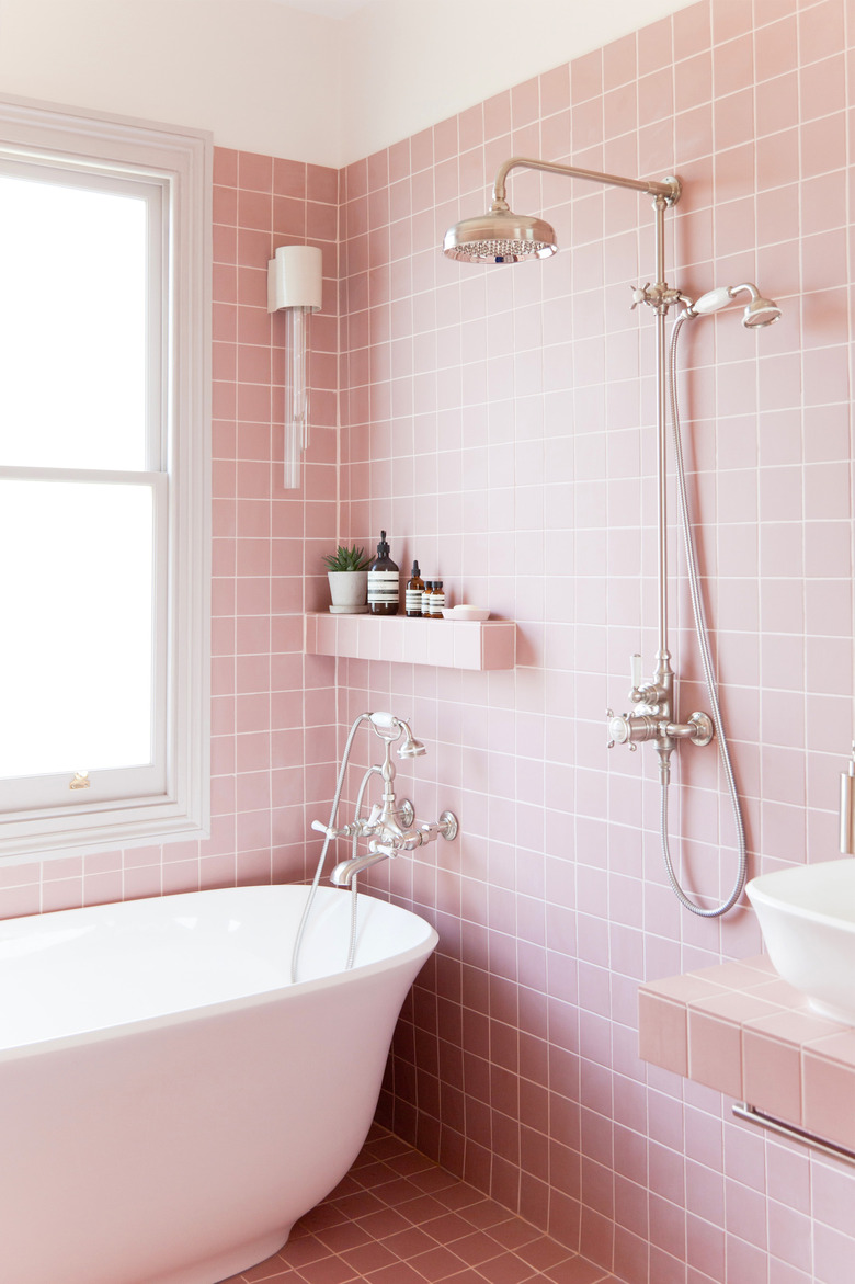 pink bathroom with freestanding bathtub and exposed plumbing