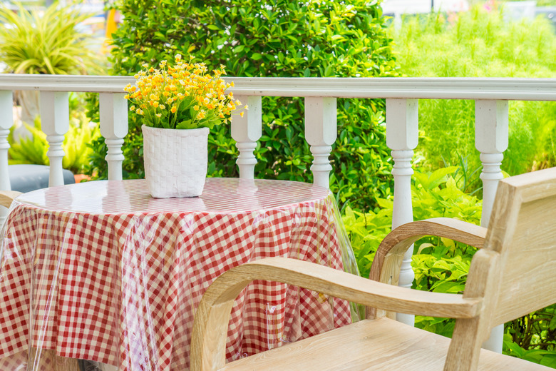 Artificial flowers and vase on table with wooden armchair