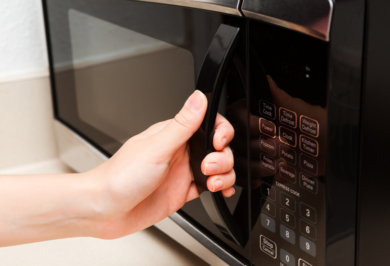 Hand holding microwave door close up