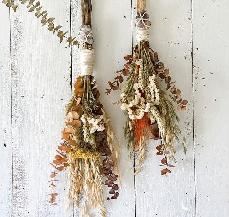 autumn besoms hanging on white wood wall