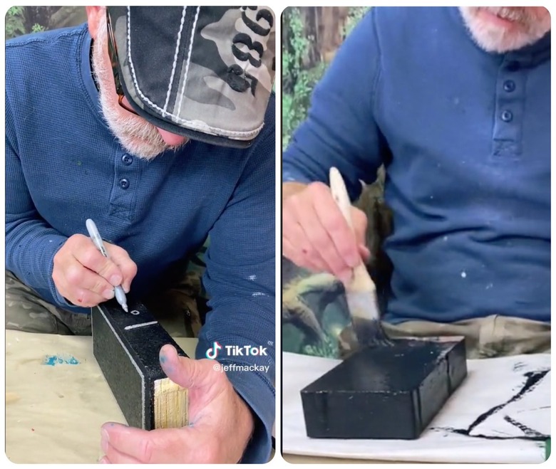 On the left is a man in a blue shirt writing a logo on a painted brick. On the right is a man in a blue shirt painting a brick black.