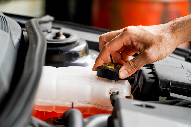 mechanic inspects the expansion tank with pink antifreeze. Vehicle coolant level in the car