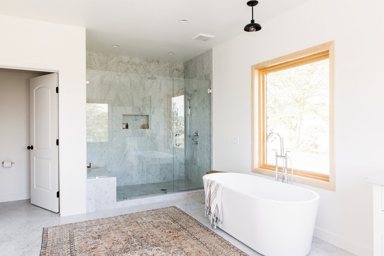 bathroom with large standing shower with glass wall, stand alone bathtub and large window