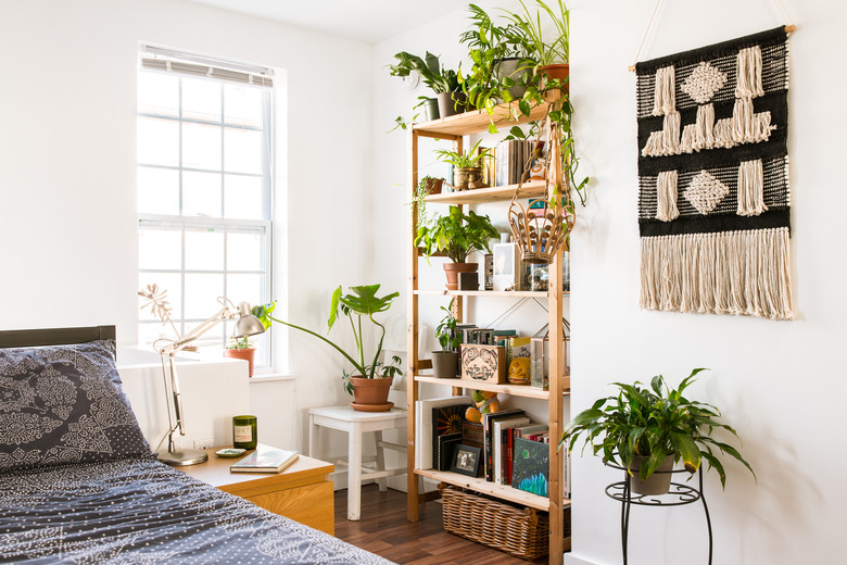 bohemian bedroom idea with potted plants on wooden bookcase and fiber wall hanging