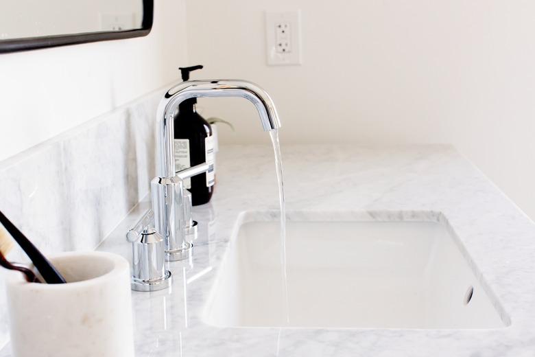 undermount sink with silver faucet, quartz countertop, white toothbrush holder