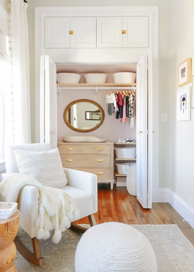 nursery organization in closet with changing table and mirror and shelving