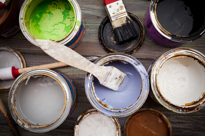 A bunch of open paint cans with brushes