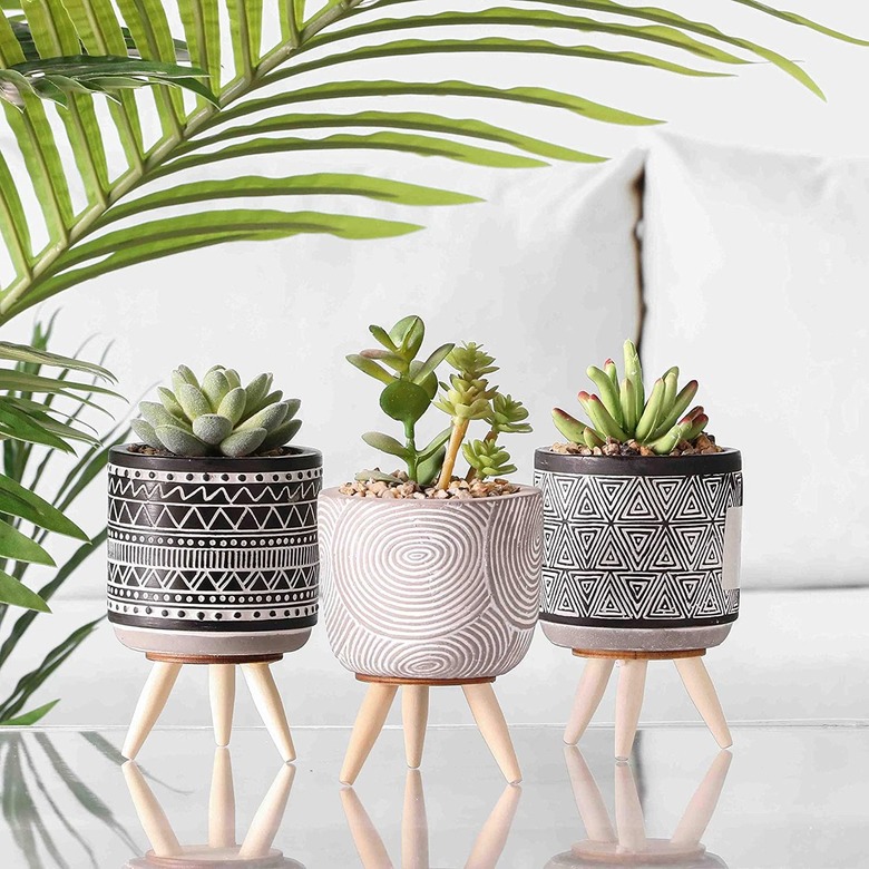 Trio of fake succulents in black and white geometric planters with long wood legs