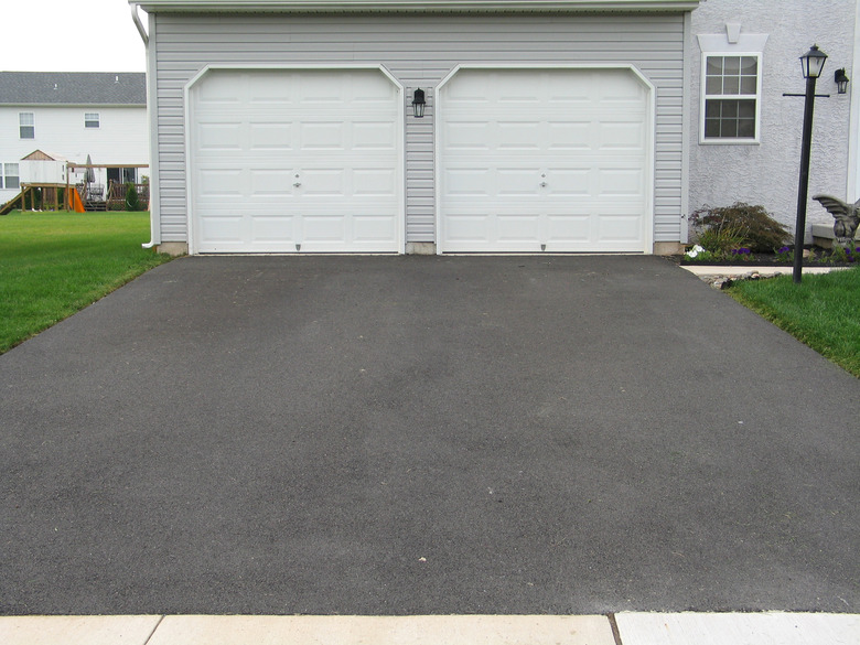 A double garage with white doors at the end of a driveway