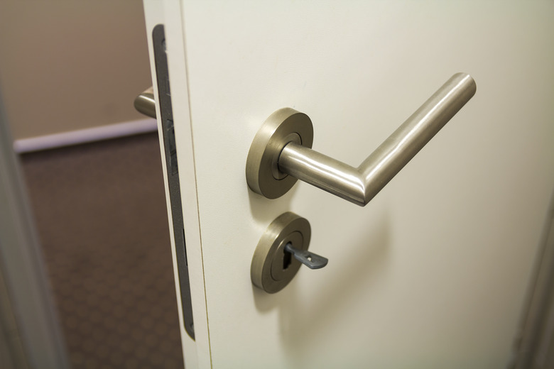 Close up of slightly open new white plastic door with bright shiny handle and keys in the lock. Safety and security of house, office.