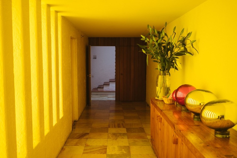 Yellow Room Ideas in Yellow hallway of a Mid-Century building, wood sideboard with plant and globes