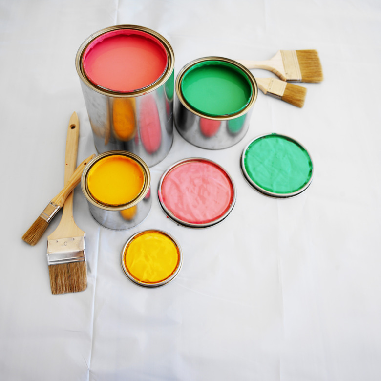 open paint cans and paint brushes on the floor