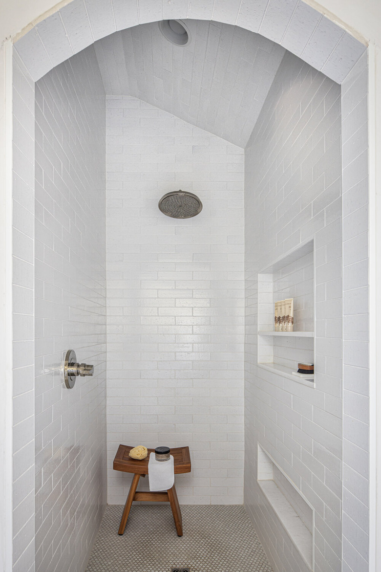 modern shower fixtures with white subway tiled walls and a wooden stool in the corner