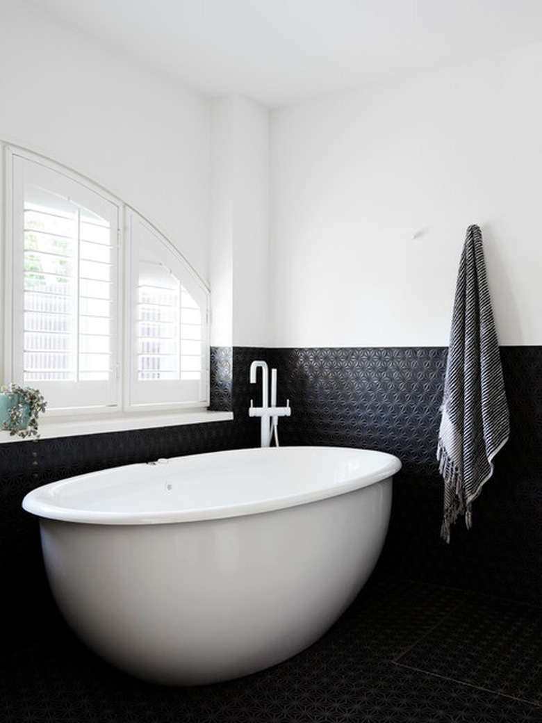 modern bath fixtures with white freestanding tub and black tile