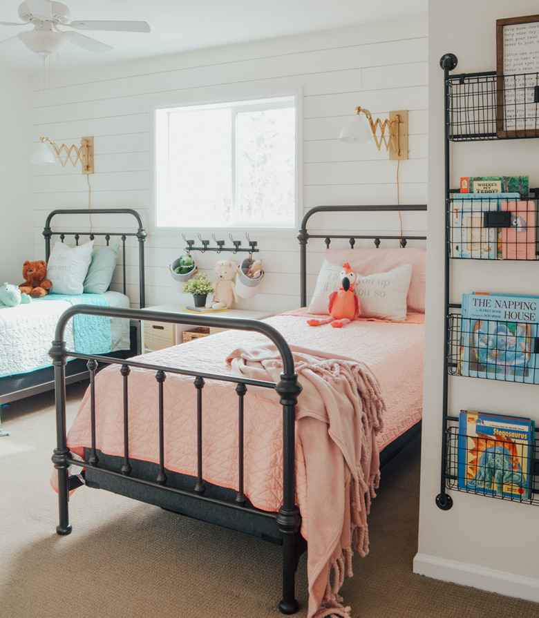 gold and glass sconces above twin cast iron beds