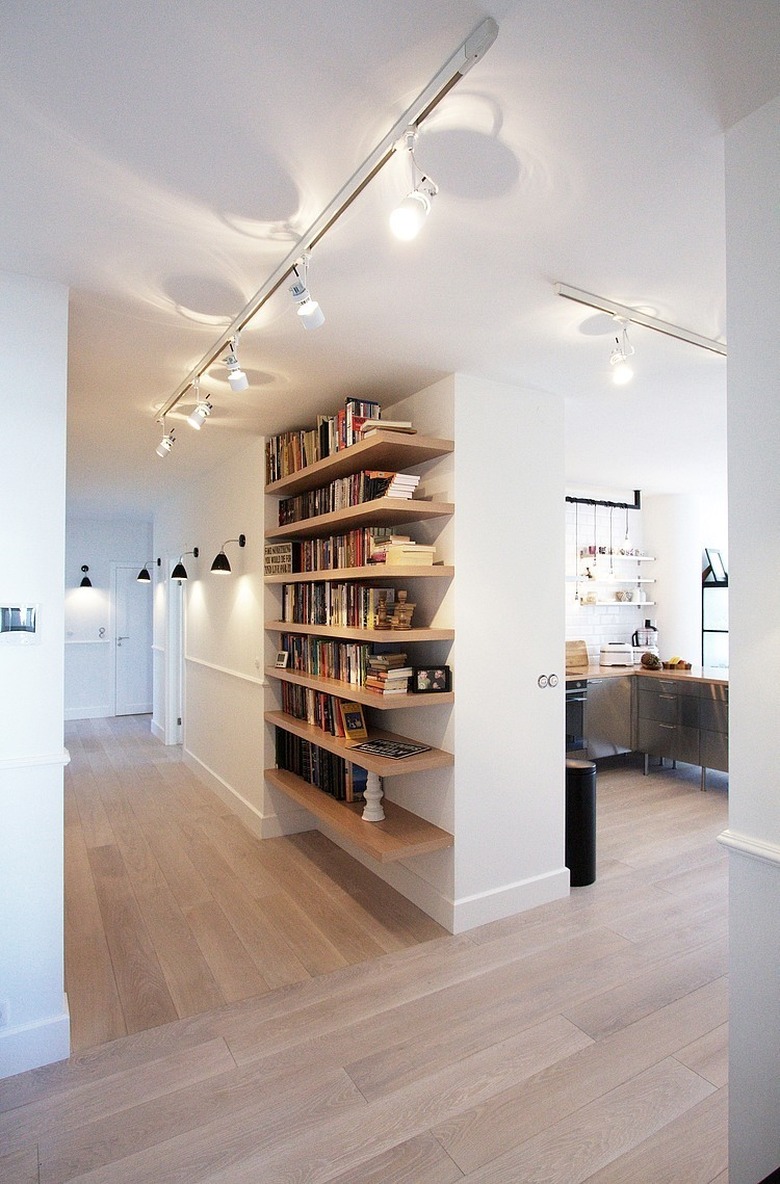 Modern Hallway with shelving, track lighting, wood floors, books.