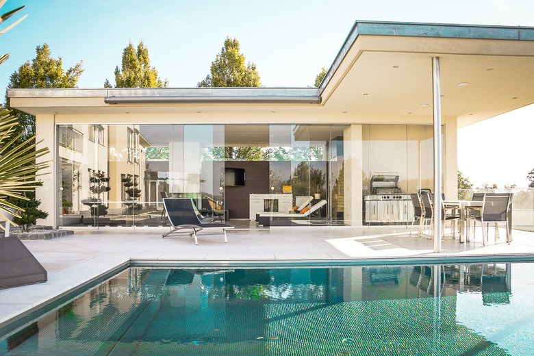 house with glass walls and pool nearby