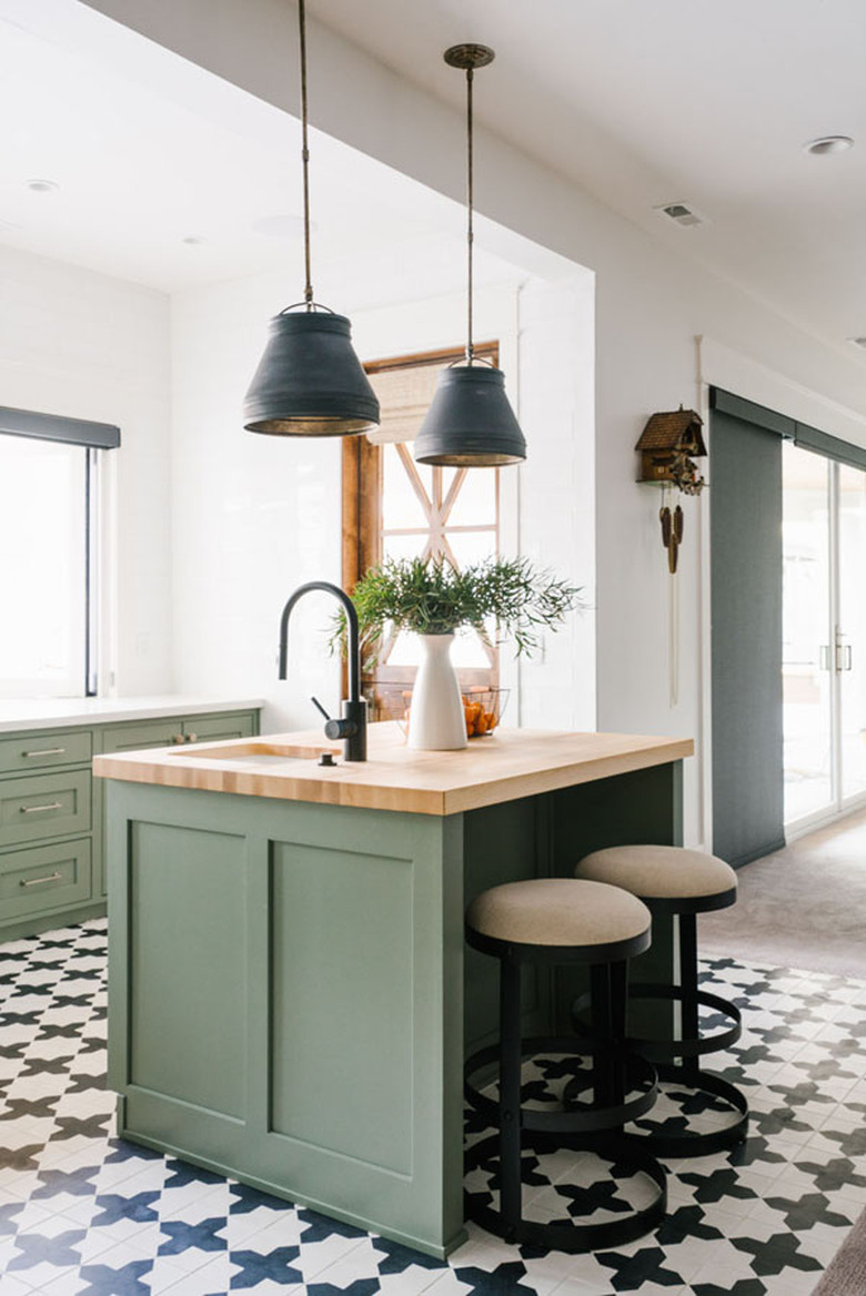 Black and white tile modern kitchen flooring in geometric shapes alongside green kitchen island