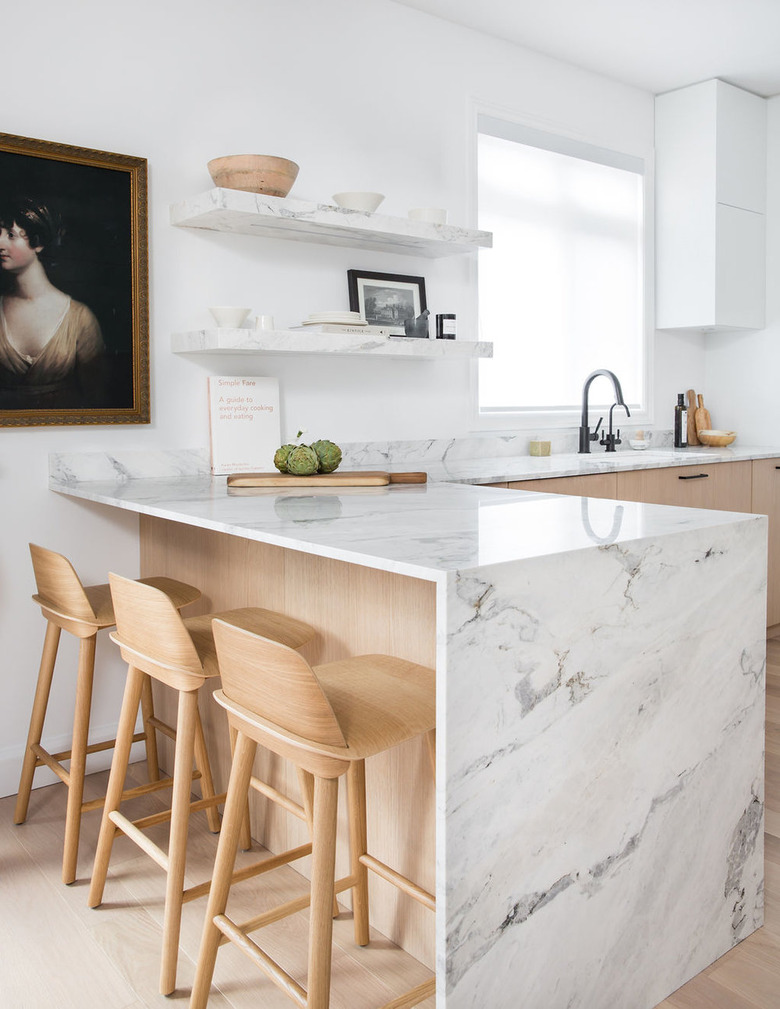 modern kitchen idea with marble waterfall countertop and light-colored woods