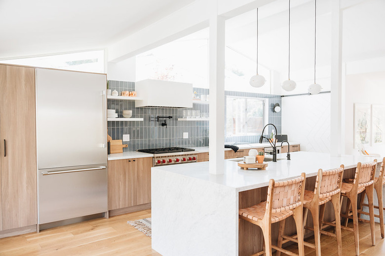 modern kitchen island with white waterfall countertop and wood cabinets