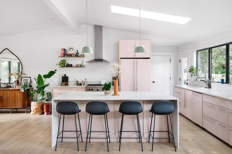 modern kitchen island in pink and white space with black stools