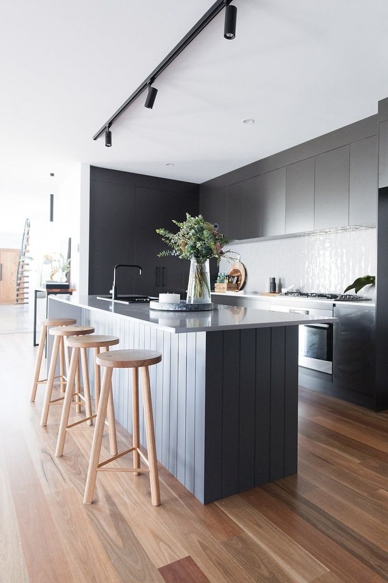 modern kitchen island with black cabinets and wood stools