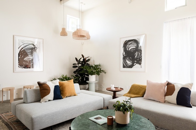 sectional couches with low backs covered in throw pillows in front of a marble coffee table