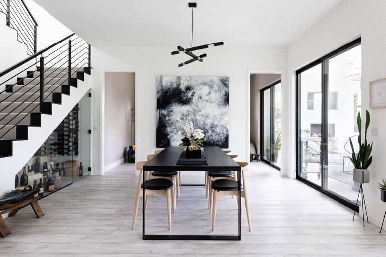 Dining room table with modern pendant lighting and large artwork