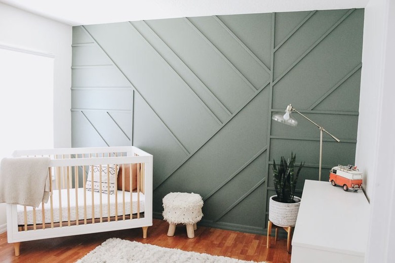 modern nursery idea with green wall panel and white crib