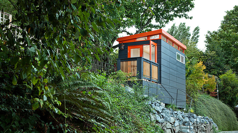 Modern shed painted orange and teal on hillside