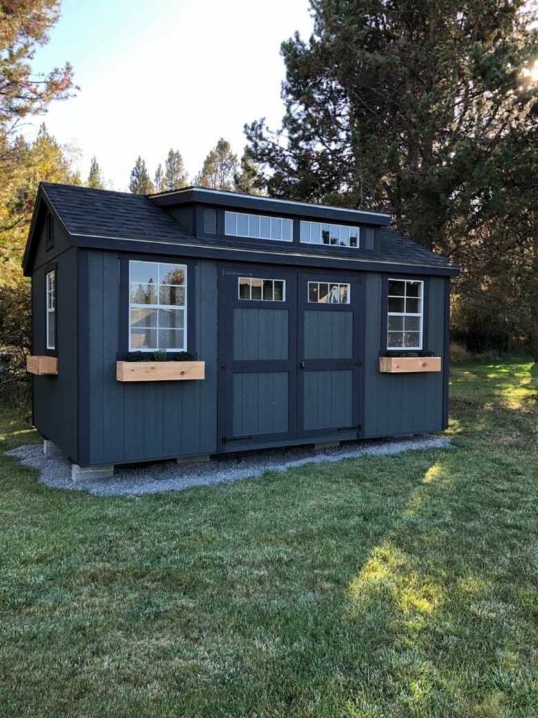 Modern shed painted black with wood flower boxes and transom windows