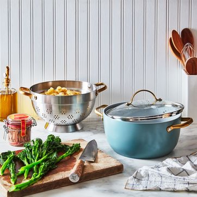 ceramic cookware in a kitchen next to a cutting board with broccoli and a knife