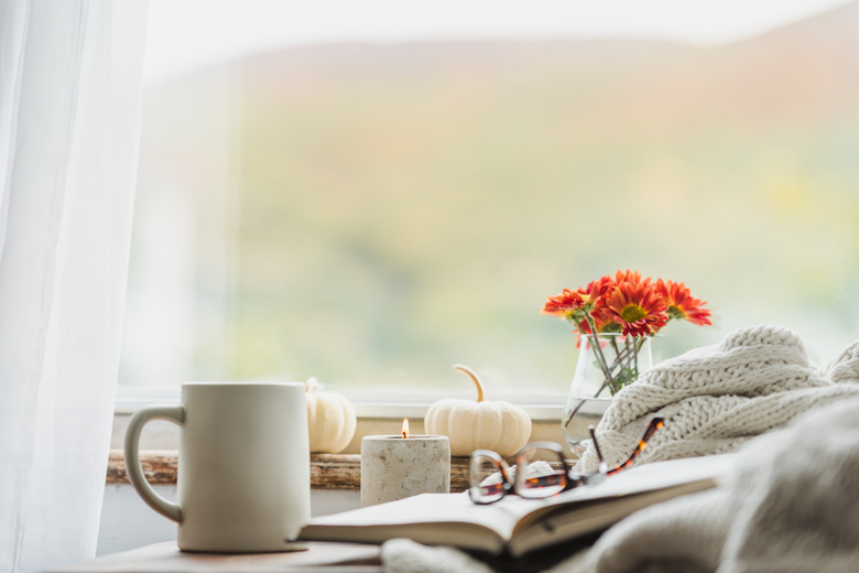 A cozy reading nook in the fall with a blanket and coffee