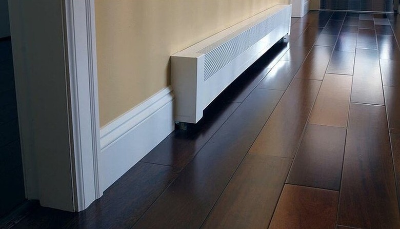 Basic Series White Galvanized Steel Baseboard Heater Cover, White Baseboard, Beige Wall, Shiny Dark Laminate Flooring