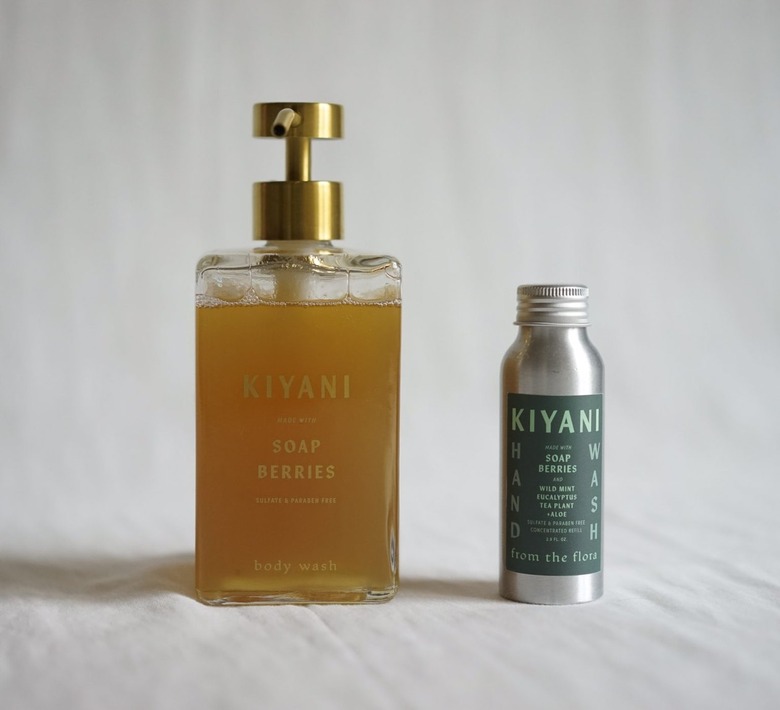 A clear bottle of yellow soap berries soap next to a small aluminum bottle of soap concentrate refill.