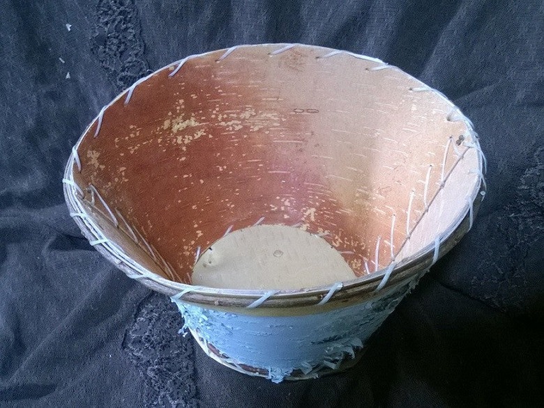 A bowl made of birch bark and twine on a black cloth.