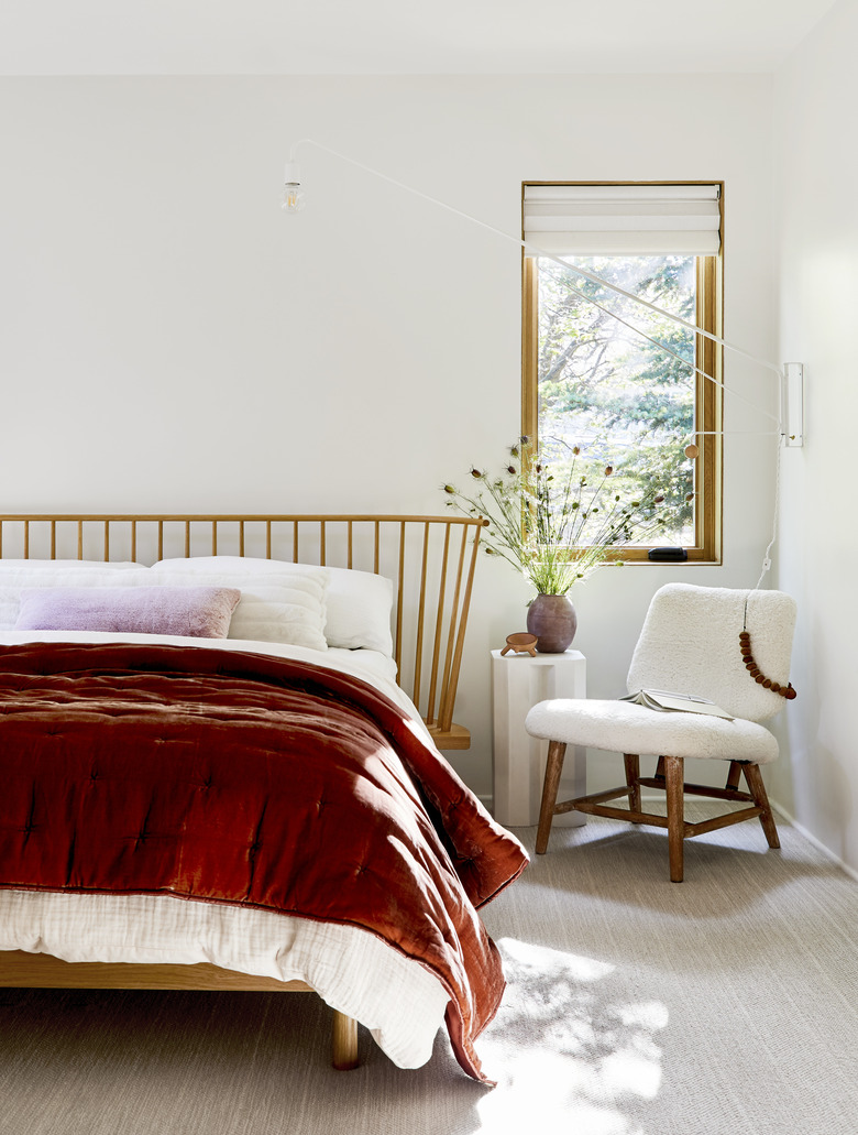 natural decor in white room with wooden bed and red quilt