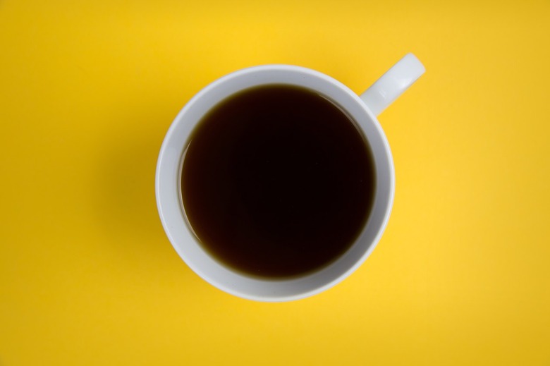 black coffee in white cup on yellow background